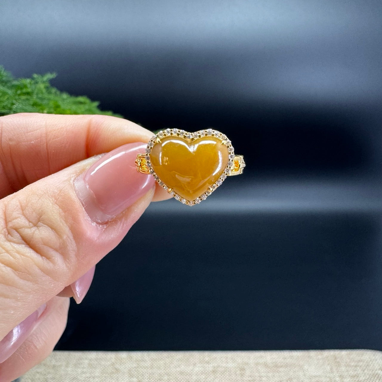 The shape of the ring is that of a heart. The jade is honey yellow color, and it is surrounded by 18k yellow gold with diamonds.