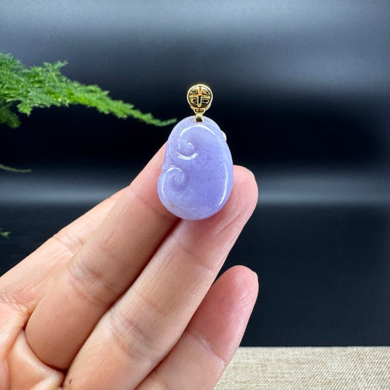 The shape of the pendant is that of a ruyi. The jade is lavender color, and it is surrounded by 18k yellow gold.