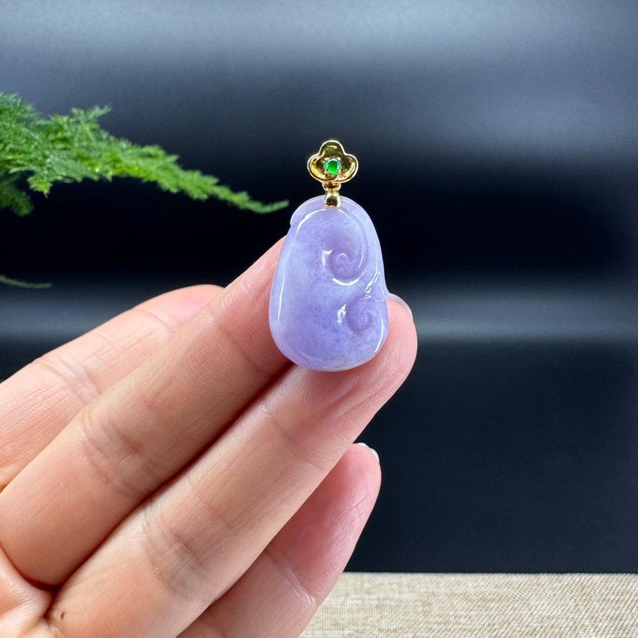 The shape of the pendant is that of a ruyi. The jade is lavender color, and it is surrounded by 18k yellow gold.