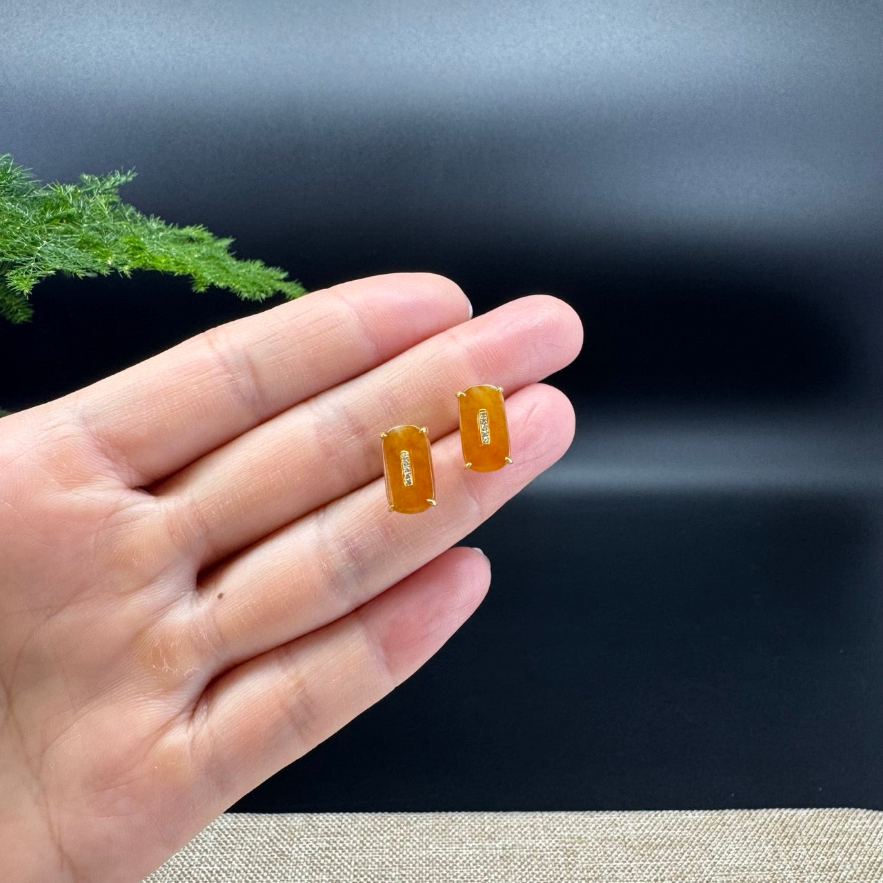 The shape of the stud earrings is that of a koukou. The jade is red color, and it is surrounded by 18k yellow gold with diamonds.